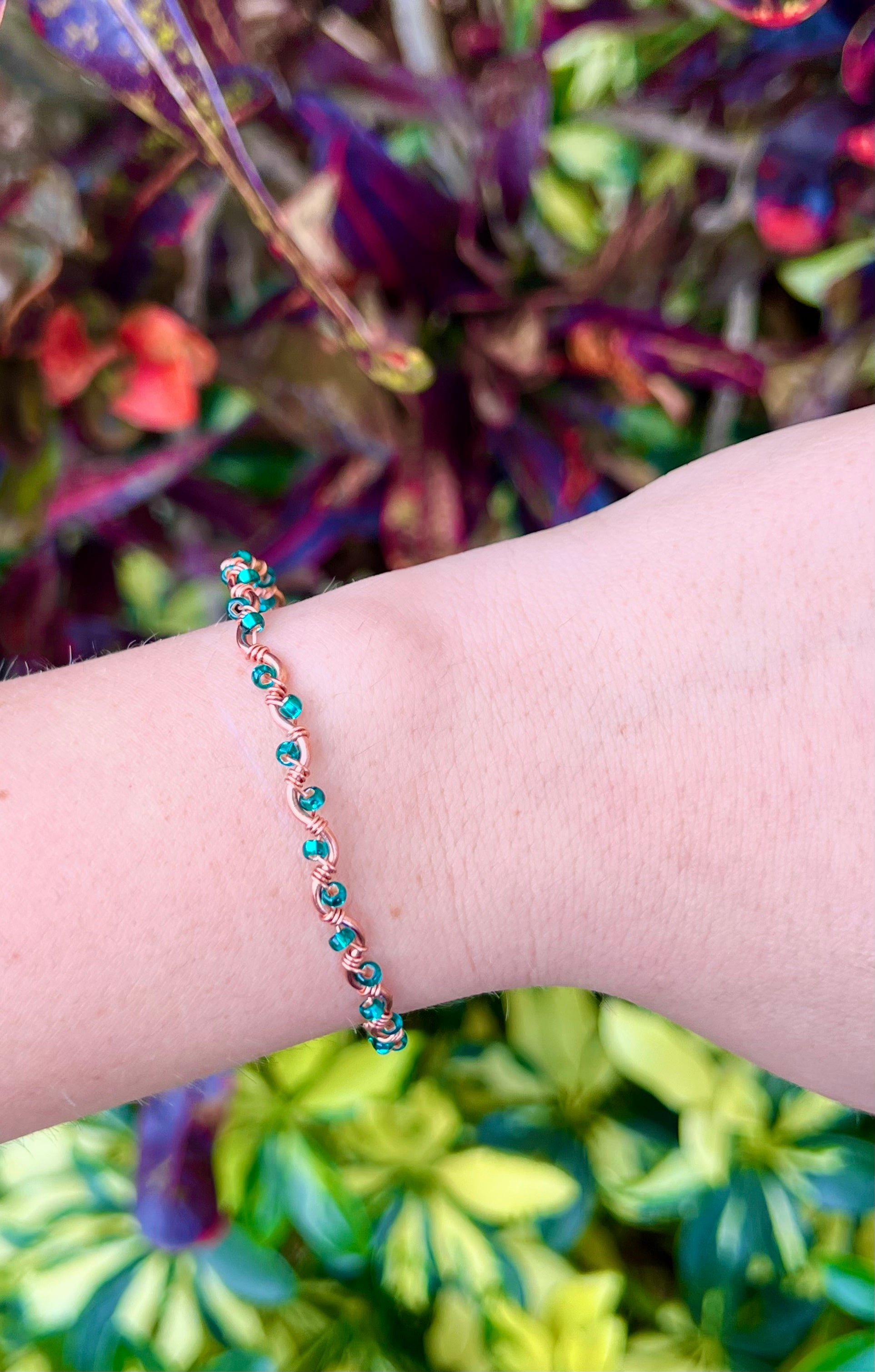 Bracelet on a wrist with a colorful background of green and purple plants