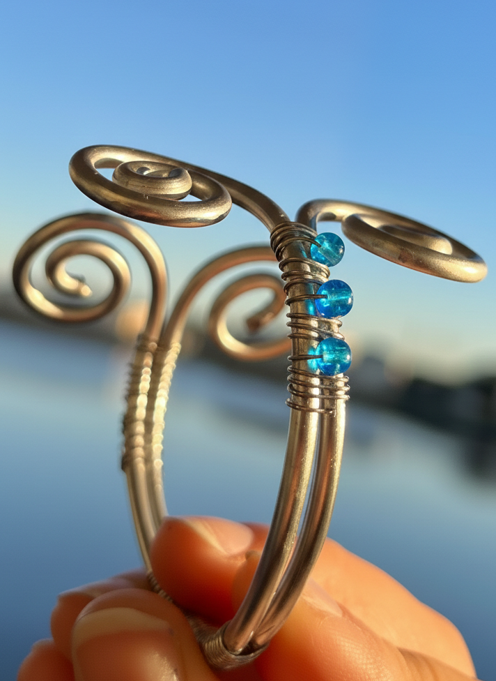 Hand holding a silver ring with blue beads against a blurred natural background