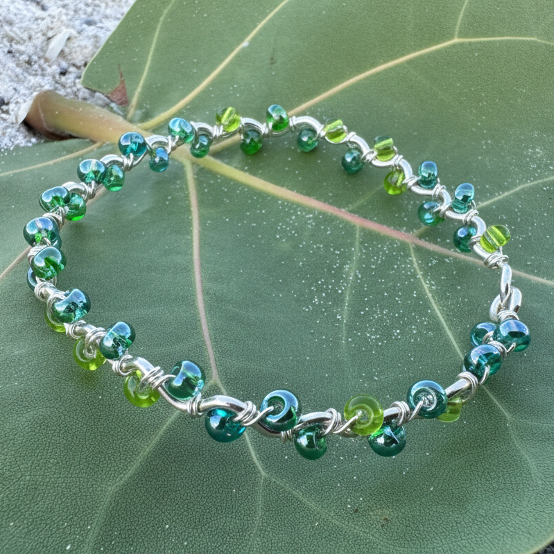 Green and blue beaded bracelet on a green leaf