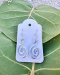 Silver spiral earrings on a purple card with green leaves in the background