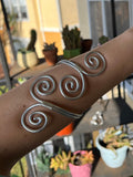 Silver spiral bracelet on a wrist with a blurred background