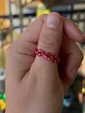 Hand holding a red beaded bracelet with a blurred indoor background