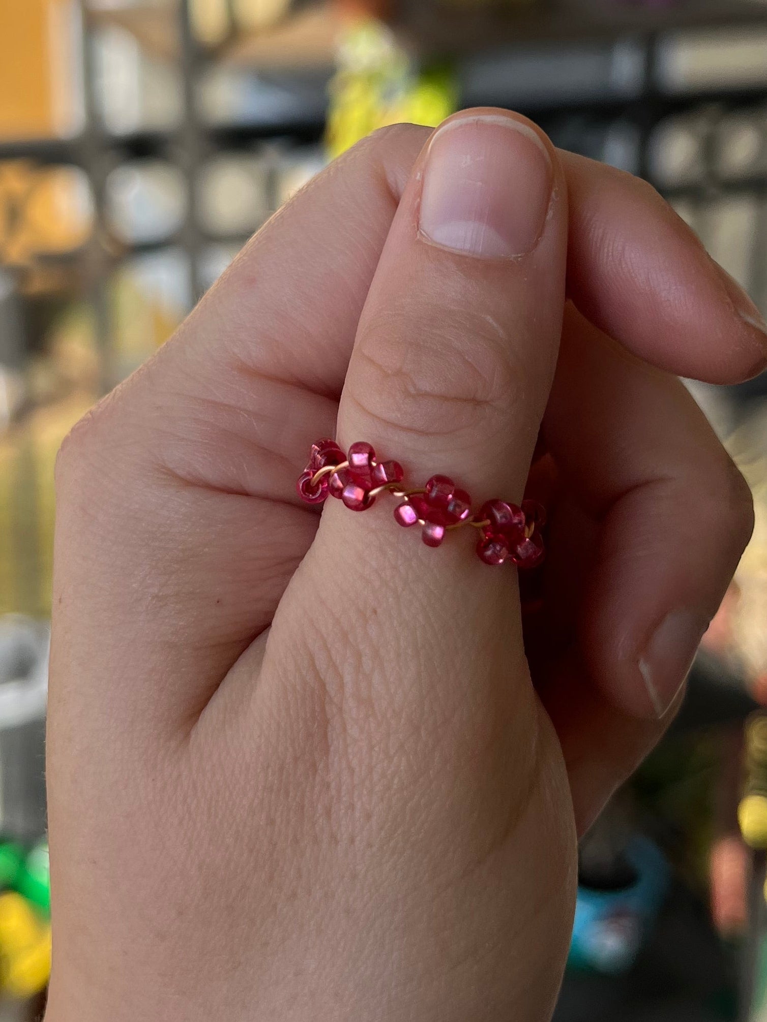 Hand holding a red beaded bracelet with a blurred indoor background