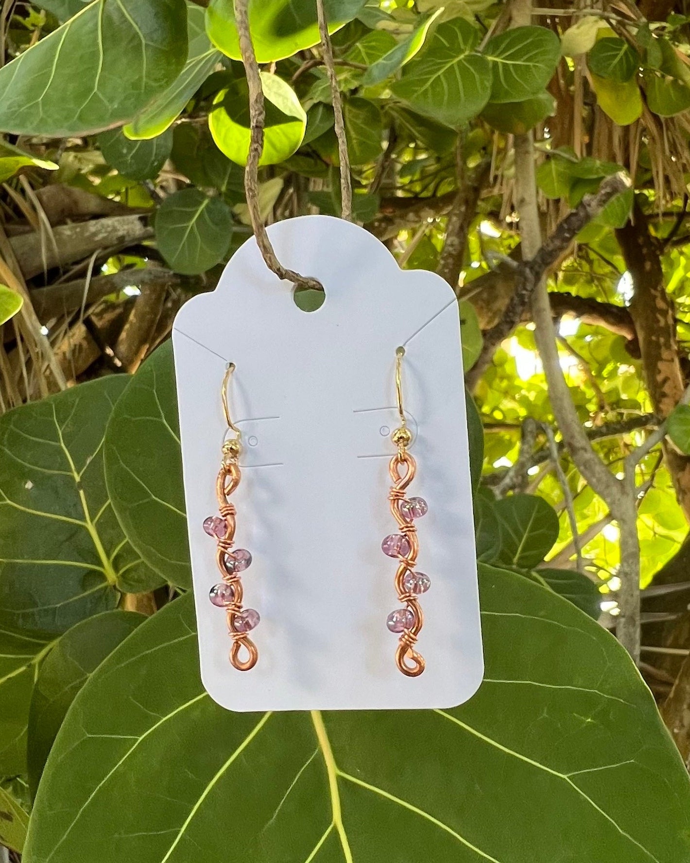 Earring card with earrings on a green leafy background