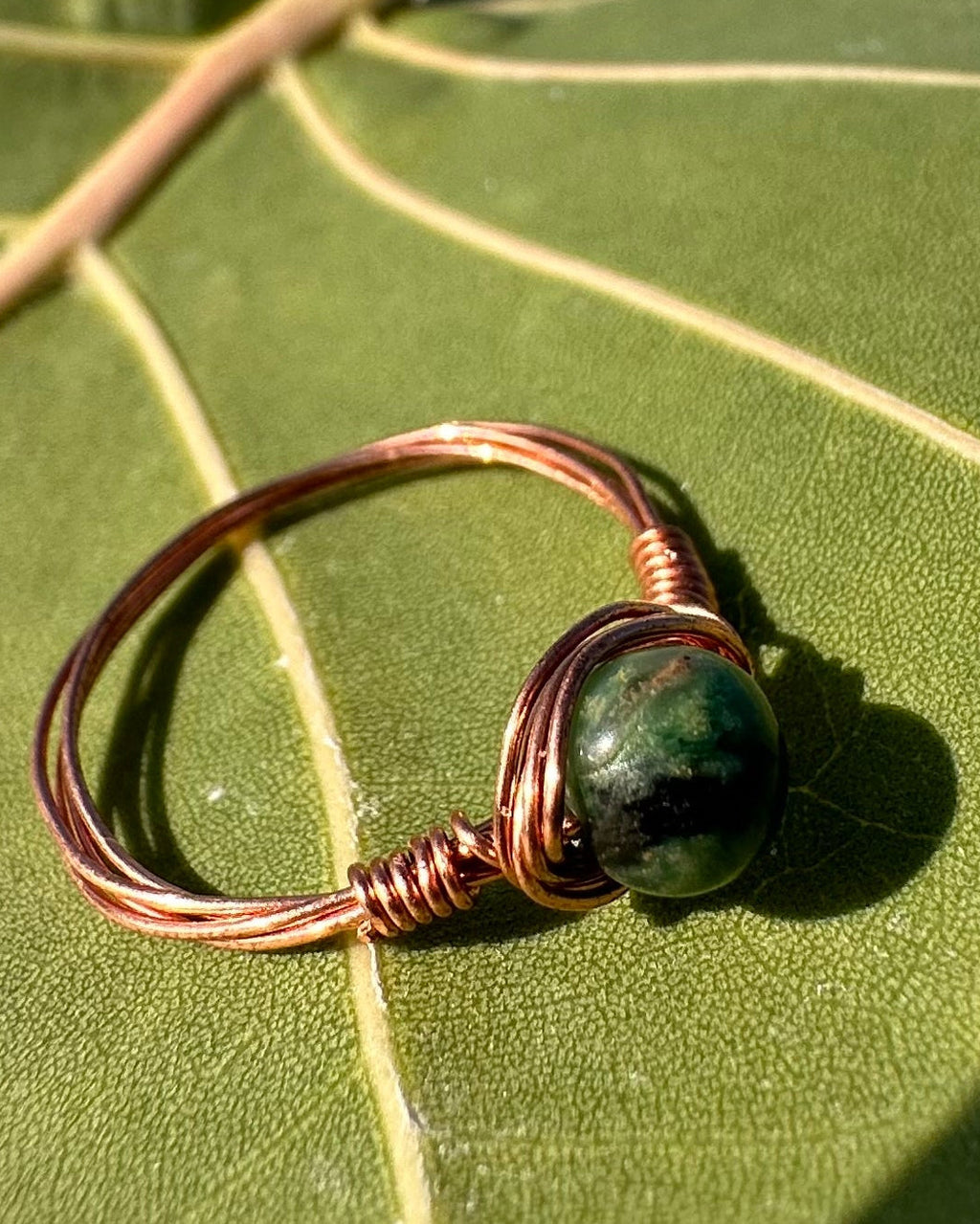 Ring with a green stone on a green leaf