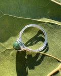 Silver ring with a green stone on a green leaf