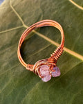 Copper ring with a purple gemstone on a green leaf