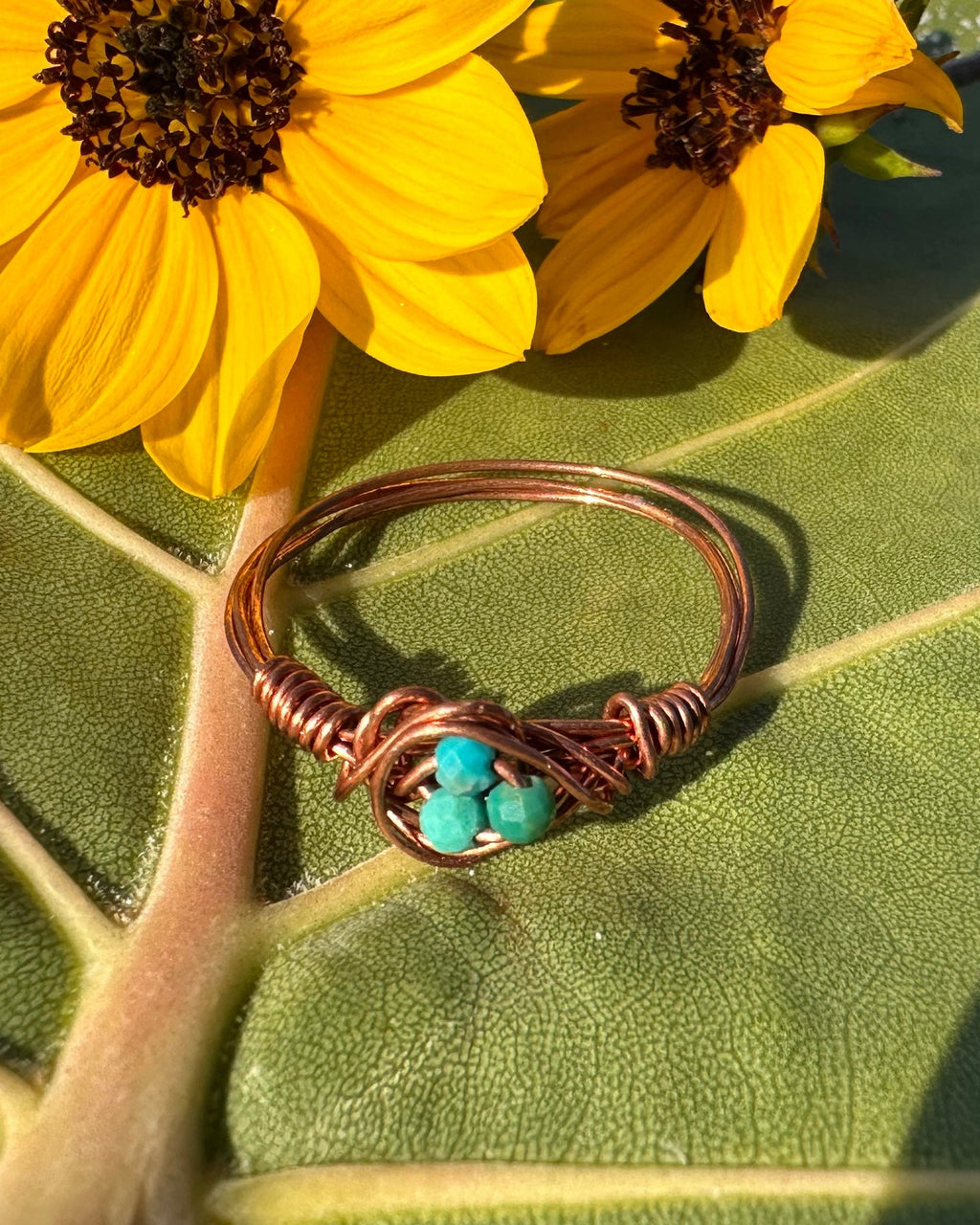 Ring with turquoise stones on a leaf with yellow flowers