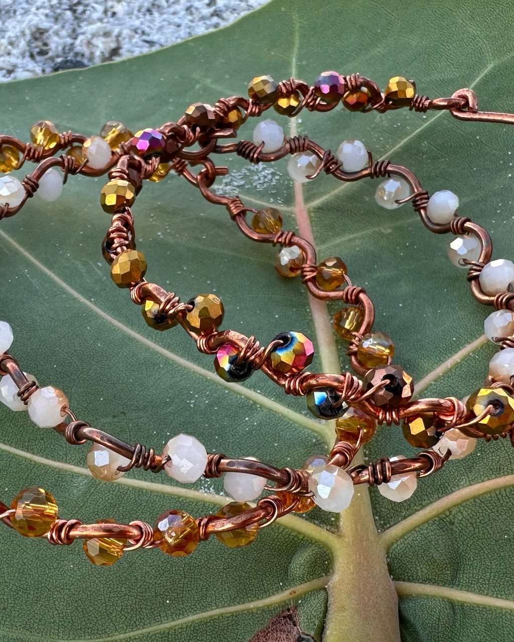 Beaded bracelet on a green leaf with a concrete background