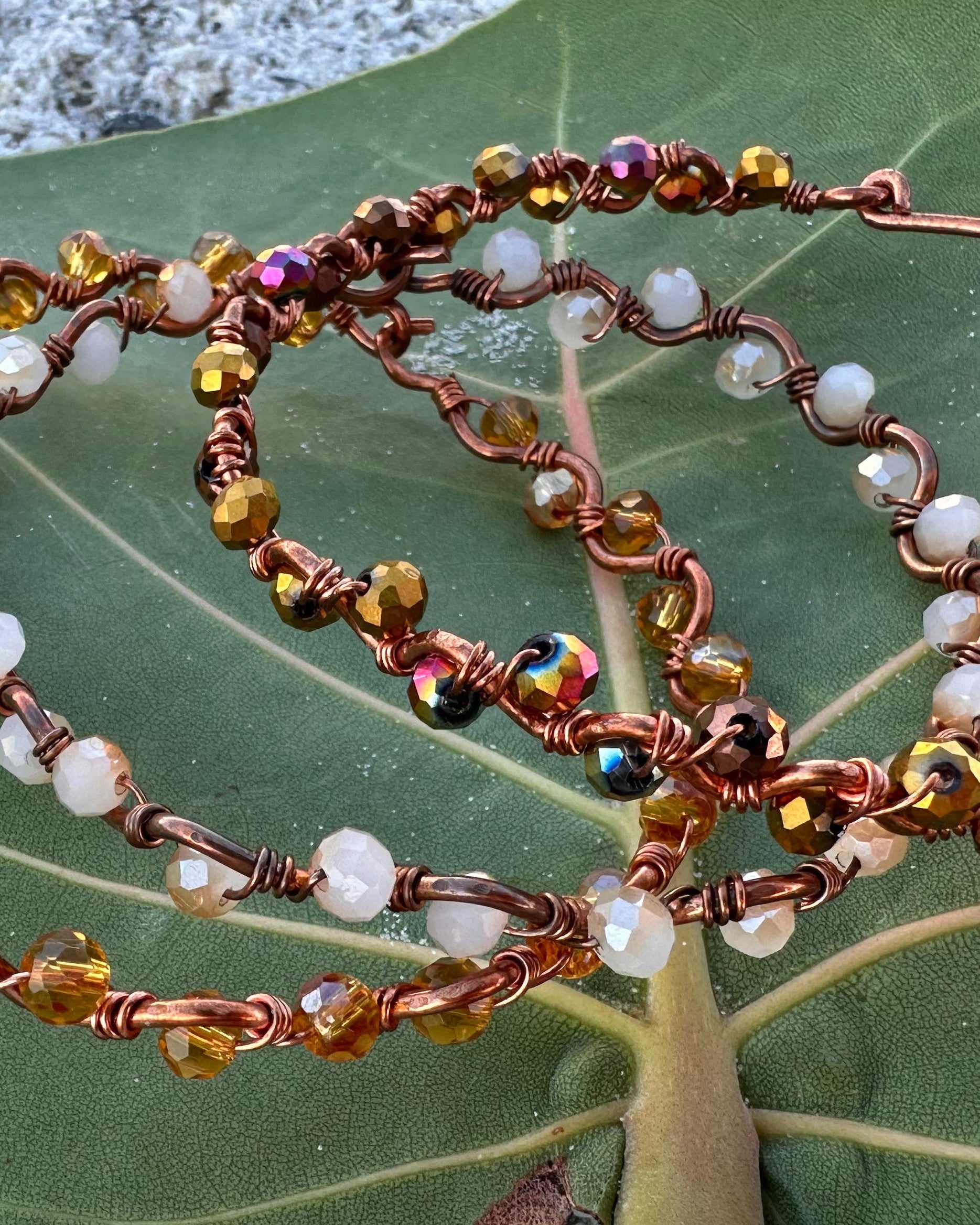 Beaded bracelet on a green leaf with a concrete background